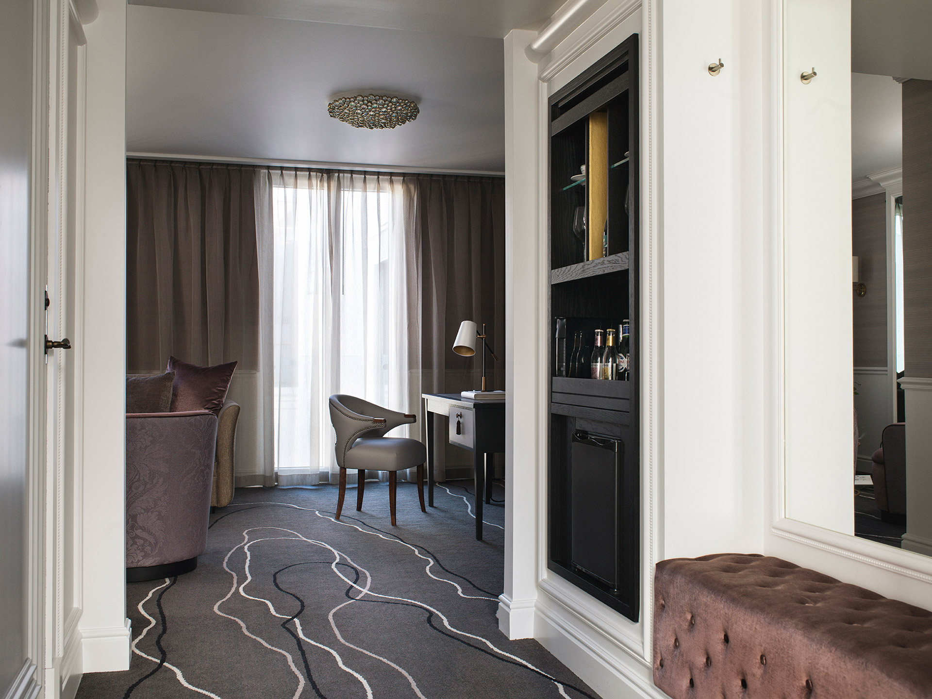 Luksuriøst hotellrom med mørke møbler og bar