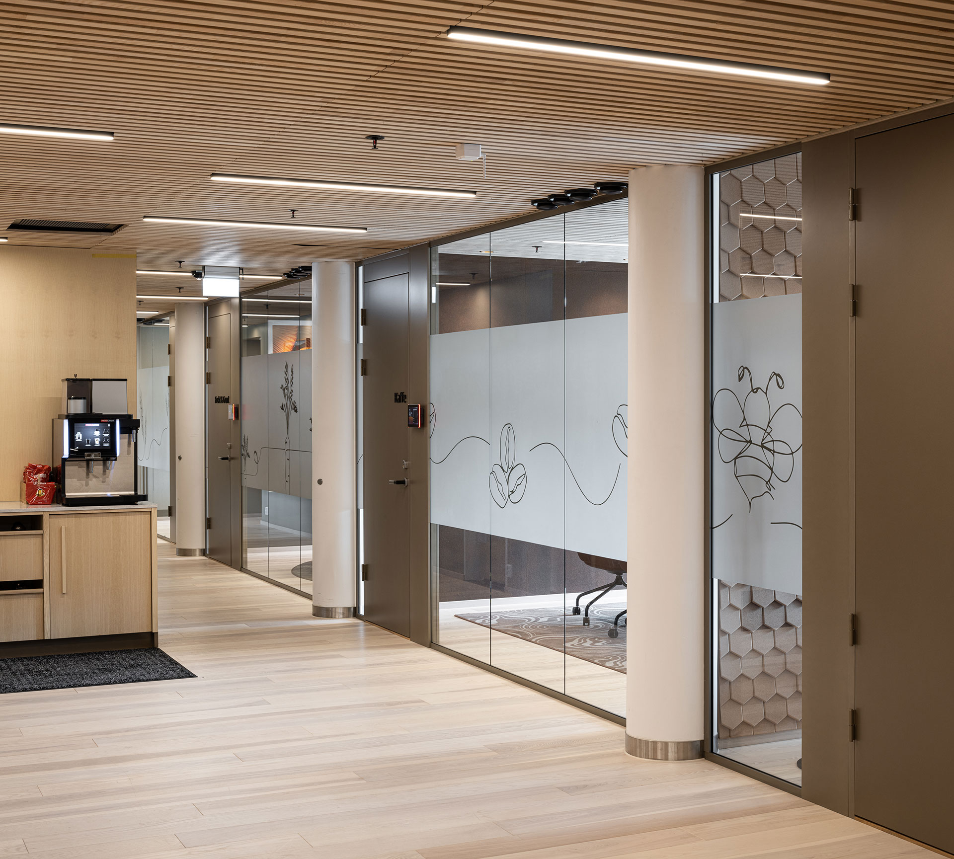 Moderne kontor med glassvegger og lysbelyst koridor