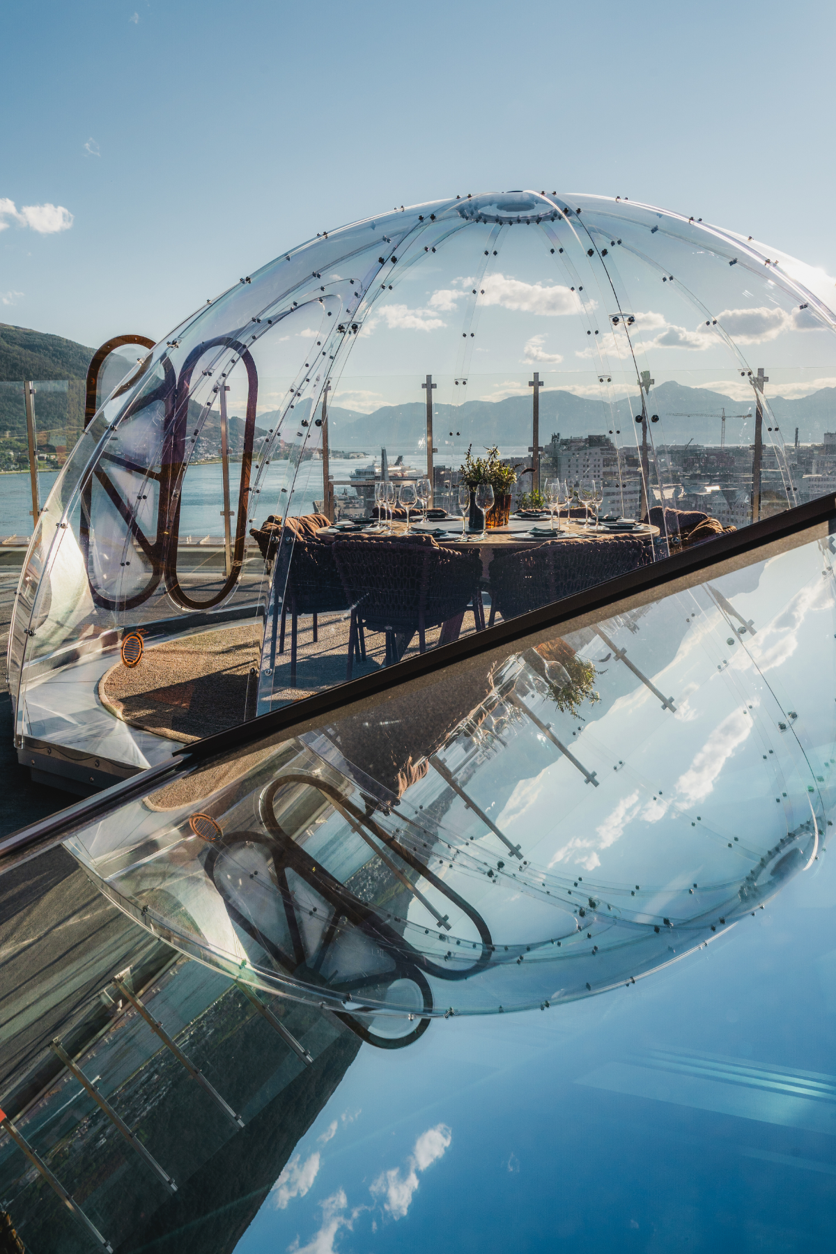 Glass iglo med utsikt over fjord og fjell