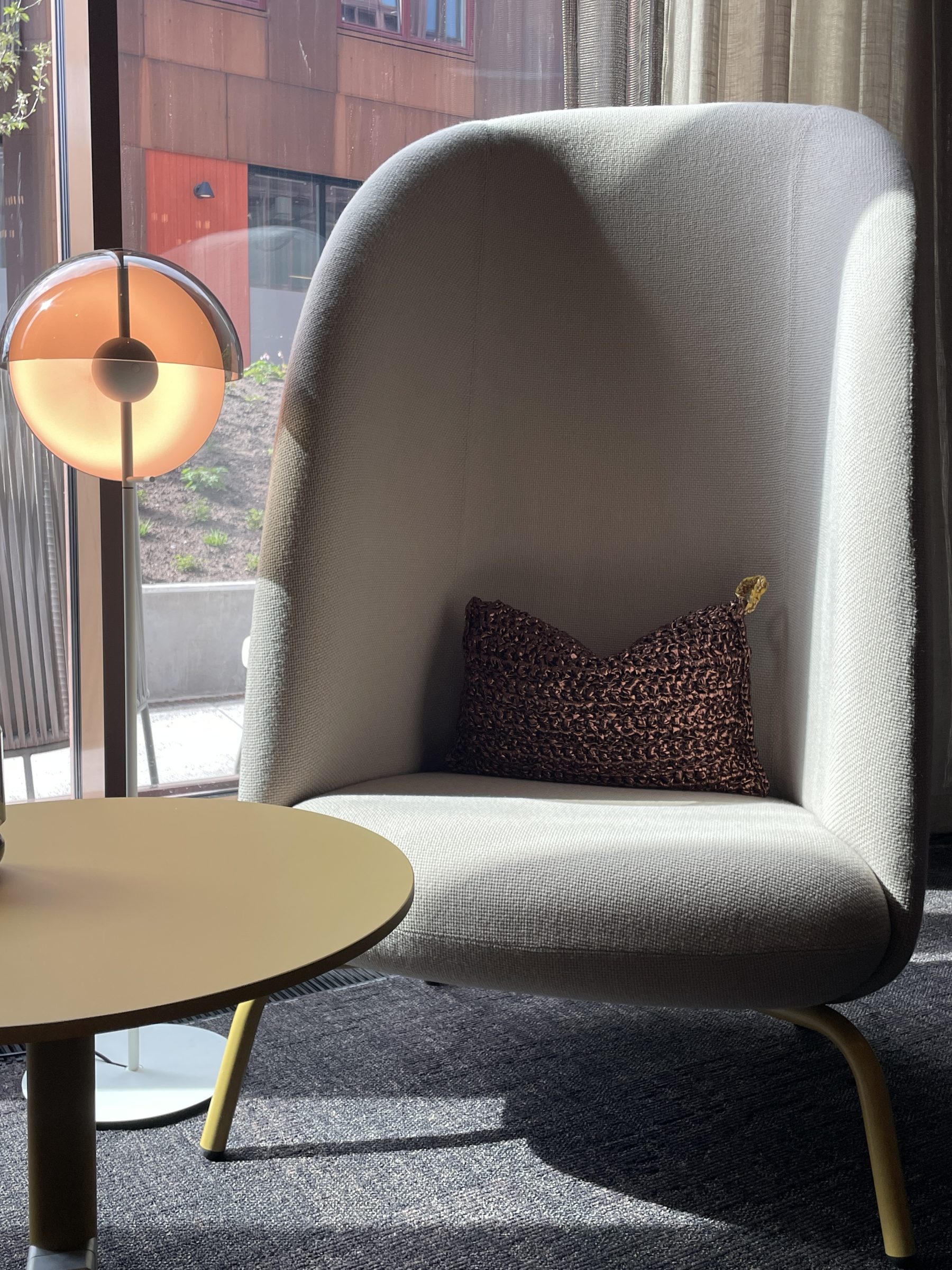 Lys grå stol med pute og lampe