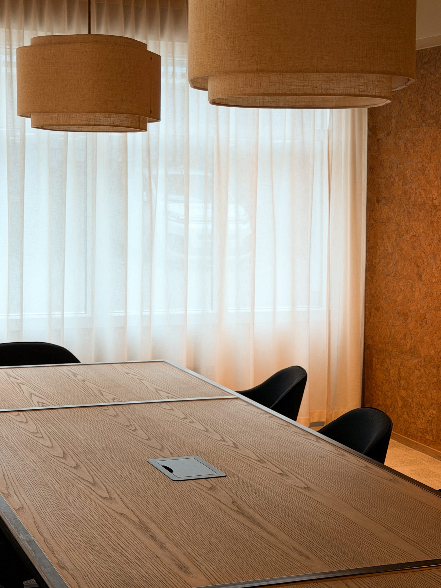 Minimalistisk møterom med trepanel og hengearmatur